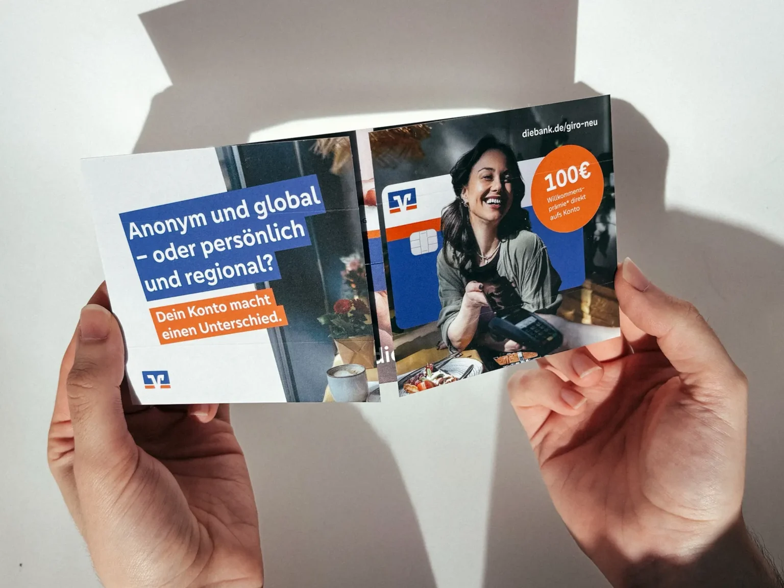 Endlosfaltkarte einer Bank in den Händen eines Empfängers – Neukunden-Mailing für ein Girokonto